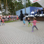 Tańczące dzieci przed sceną i publiczność, na scenie orkiestra