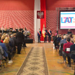 Sala gimnastyczna - uczestnicy, orkiestra, poczet sztandarowy, przemawiająca Dyrektor ZSE A. Niczyporuk