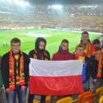 Uczniowie z flagą Polski na tle stadionu