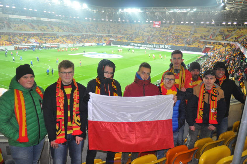 Uczniowie z flagą Polski na tle stadionu