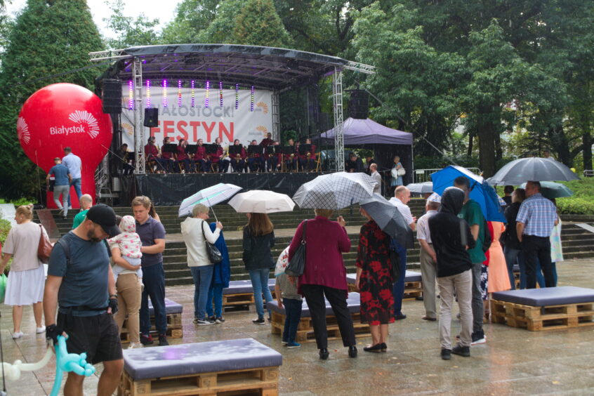 Orkiestra dęta ZSE na scenie i publiczność pod parasolami